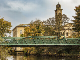 Green iron footbridge across the River Aire to Roberts Park in the Unesco World Heritage Site model...