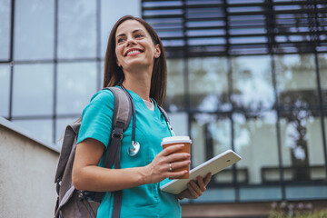 Smiling Nurse Holding Coffee and Tablet Outside Hospital