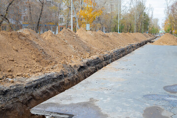 a long, narrow, deep trench on a city roadway for laying a city water pipeline or water pipe. Repair repair of city water supply in a deep trench on a city street. Improving the quality of life