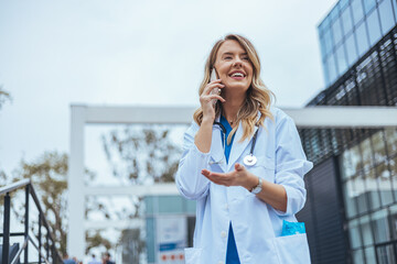 Smiling Female Doctor Talking on Phone Outside Modern Building
