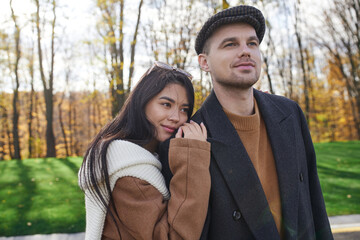 A couple sharing a tender moment amidst vibrant autumn foliage, showcasing their affection.
