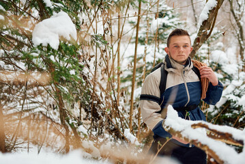 A determined mountaineer sails through a peaceful snow-covered forest, equipped with a rope and a backpack, embodying the spirit of adventure in the heart of winter.