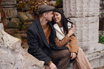 A charming couple sits together in the autumn landscape, radiating warmth and affection.