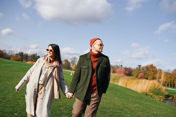 A loving couple enjoys a cozy walk together in a picturesque autumn landscape.