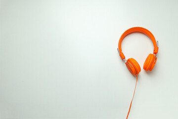 On-top, large, bright orange headphones, on a light background.