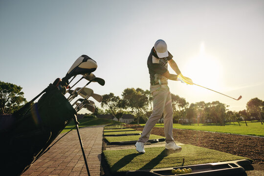 Golfer refining his swing on resort driving range under the evening sun