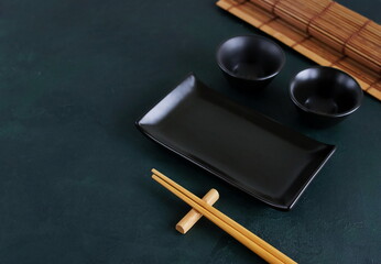 Empty sushi plates and chopsticks top view on dark textured background template with copy space.