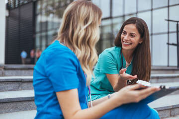 Two Nurses Sharing a Relaxed Moment on Hospital Steps