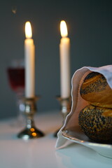 vertical photo Shabbat or Sabbath kiddush ceremony composition with a traditional sweet fresh loaf of challah bread, glass of red kosher wine and candles on a vintage wood table with copy space