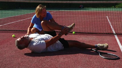 Athletic senior tennis player suffers leg injury on the court while his wife comforts him - Powered by Adobe