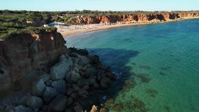 Drone flight over Cala del Aceite in Cadiz, Andalucia, Spain. People enjoying a summer day on a beach with crystal clear water. Mediterranean coast