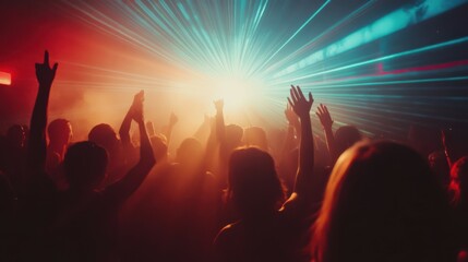 Fototapeta premium People dance in club spotlight laser lights with hands up in cinematic photography style. People crowd dancing at techno, rave or electronic music club