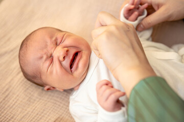 Mother wearing clothes to her baby. Baby healthcare hygiene concept.
