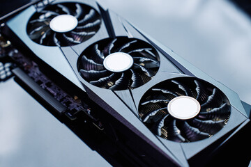 Close-up of high-performance graphics card with three cooling fans on dark background. Modern video...