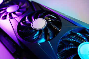 Close-up of high-performance graphics card with three cooling fans with neon lighting. Modern video...