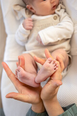 Parent holding in the hands feet of newborn baby. Mom holding baby feet.