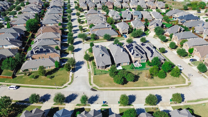 Fototapeta premium Residential street in upscale new development neighborhood row of two-story suburban houses solar panel roofing, compact backyard, well-trimmed landscape in Argyle, Denton County, Texas, aerial