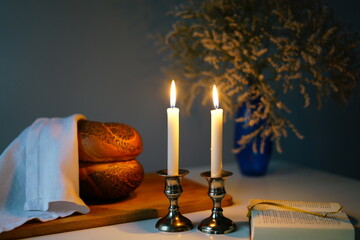 Traditional challah bread with wine and glowing candles on dark background. Shabbat Shalom