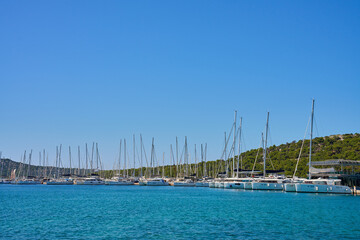 Row of luxury yachts docked in marina under a clear blue sky on sunny day