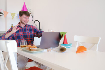 Young man video chatting with family on his birthday, smiling and joyful as he connects with loved ones from home, celebrating special day with warmth and connection
