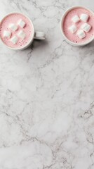 Two cups of pink hot chocolate topped with marshmallows on a marble surface.