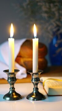 Shabbat or Sabbath kiddush ceremony composition with a traditional sweet fresh loaf of challah bread, glass of red kosher wine and candles on a vintage wood table with copy space