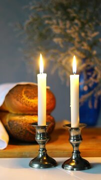 Shabbat or Sabbath kiddush ceremony composition with a traditional sweet fresh loaf of challah bread, glass of red kosher wine and candles on a vintage wood table with copy space