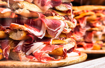Traditional Spanish bocadillos with Iberico jamon laid out in a slide on a shop window