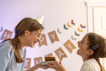 Birthday concept. The girl blows candles on the cake.