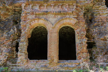 Fragment of ruined brick wall with arched window openings