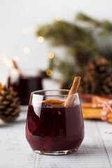 Cozy mulled wine with cinnamon and orange, surrounded by pinecones and festive decor on a rustic table
