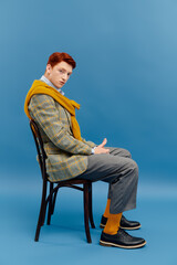 A young man with striking red hair showcases a layered winter outfit, exuding style and confidence.