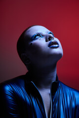 A young woman with short pink hair displays her unique style and confidence in a vibrant studio environment.