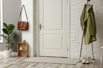 Metal rack with green coat and sneakers in hallway