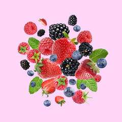 Mix of fresh berries in air on pink background