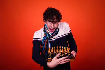 A funny young attractive guy with a curly hairstyle poses in the studio.