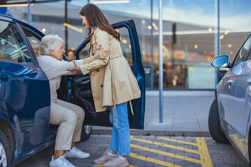 Young Woman Assisting Elderly Lady out of Car at Parking Lot