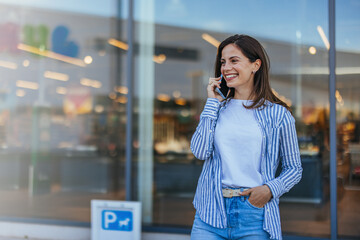 Happy Woman Talking on Phone Outside a Modern Storefront