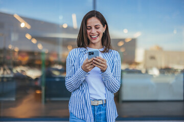 Smiling Woman Enjoying a Message on Her Smartphone Outdoors