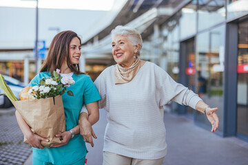 Caregiver Assisting Senior Woman with Shopping and Flowers Outside