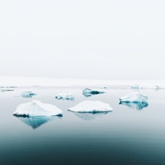 Obraz premium Icebergs floating in a calm, reflective sea under a misty sky.
