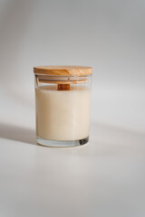 Wax scented candle in glass beaker with wooden lid on white background.