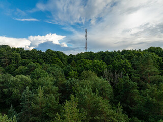 Aerial photo of a dense forest of various shades of green stretches out, with tree canopies forming a rich, verdant blanket. Cell tower rising above the treetops. Turisalu (Estonian T&uuml;risalu), Estonia