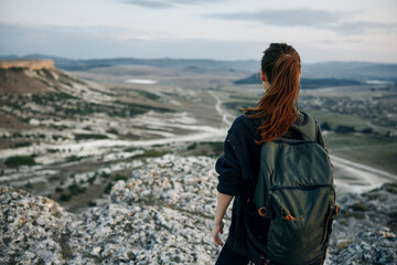 Majestic view woman on mountain peak gazes over vast valley below with backpack in tow