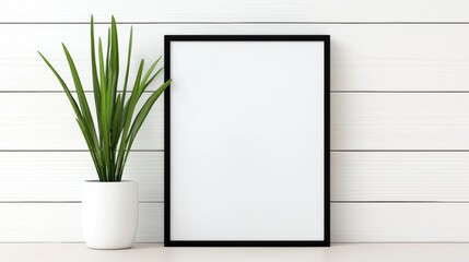 Minimalist photo frame mock-up concept. A minimalist scene featuring a blank frame beside a green plant set against a white wooden background