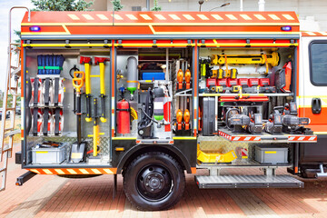 Firefighter equipment organized in compartments on a truck featuring tools, hoses, helmets for...