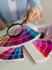 A designer examining color swatches with a magnifying glass for a project
