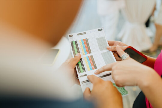 A golfer marks a score on a golf scorecard concept - Powered by Adobe