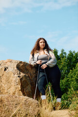 A confident plus size woman stands in a serene field, soaking in the natural beauty around her.