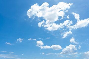 Fluffy white clouds drift across a bright blue summer sky